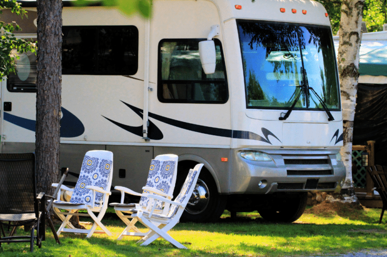 A white RV parked in a park, surrounded by trees and nature. Perfect for RV camping in Idaho.