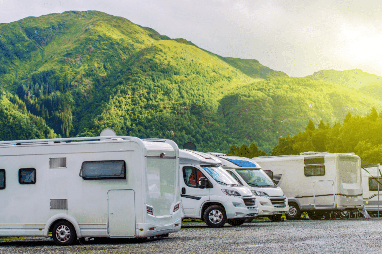 Several motor homes parked in RV park lot with amenities.